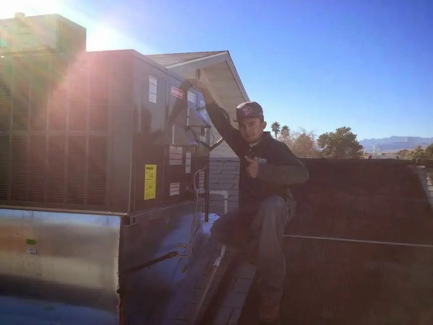 HVAC technician performing Boiler Repair on a rooftop unit in Woodburn